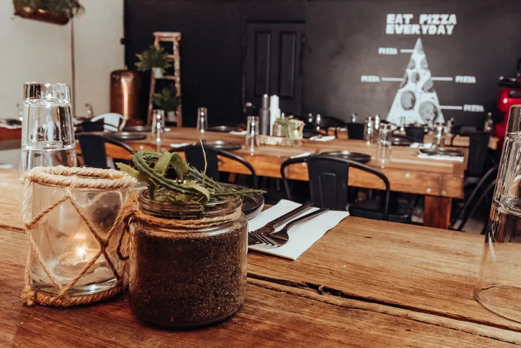 A table laid with a candle jar and a succulent, long tables set for a function behind it